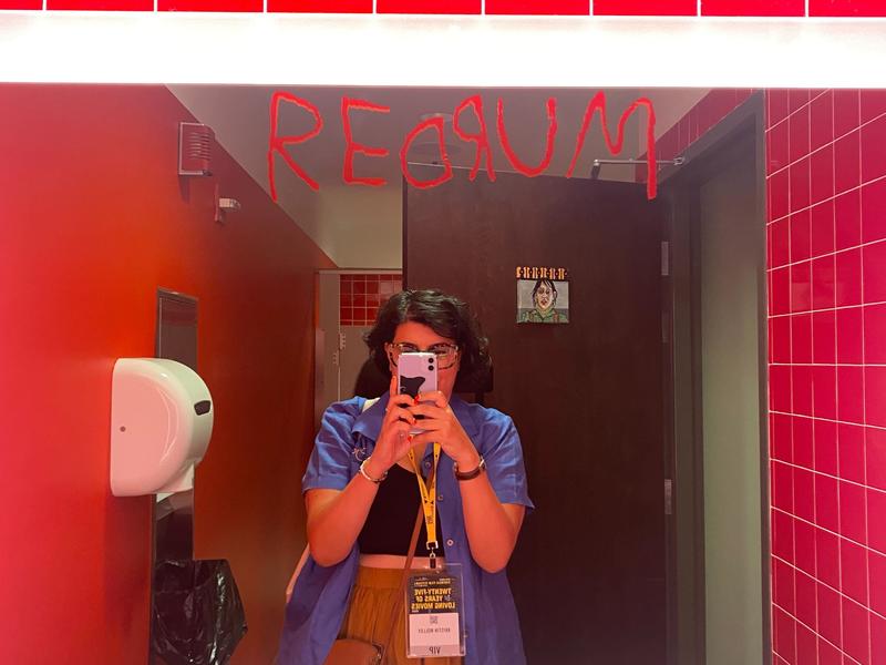 [Image description: A bathroom mirror selfie of Kristin Molloy. The mirror has "REDRUM" written on it in the style of "The Shining" (1980)]