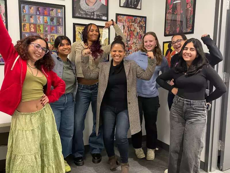 [Image description: Alex Ruiz and the 2024 Incubator cohort in front of a wall of puzzles]