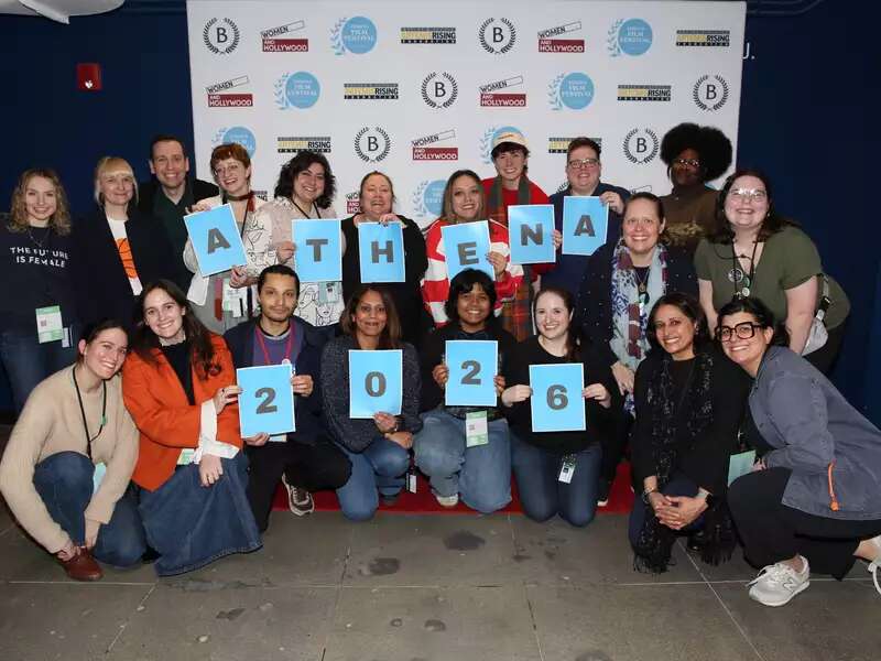 [Image description: the 2025 Athena Film Festival staff and volunteer team in front of the AFF backsplash. The team is holding signs that read "Athena 2026"]